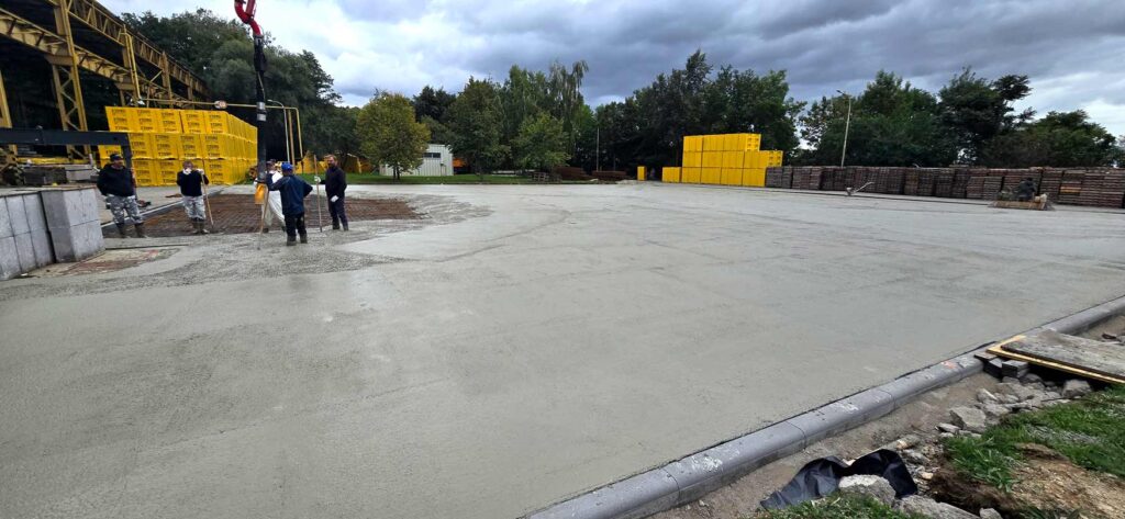 Postup betonáže velké zpevněné plochy s pracovníky na stavbě.