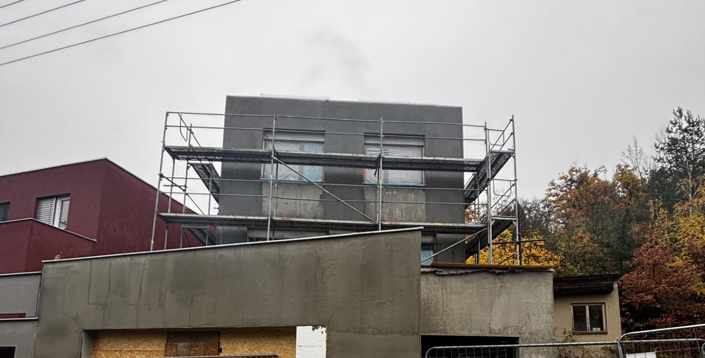 Detail rozestavěného rodinného domu s lešením a hrubou fasádou