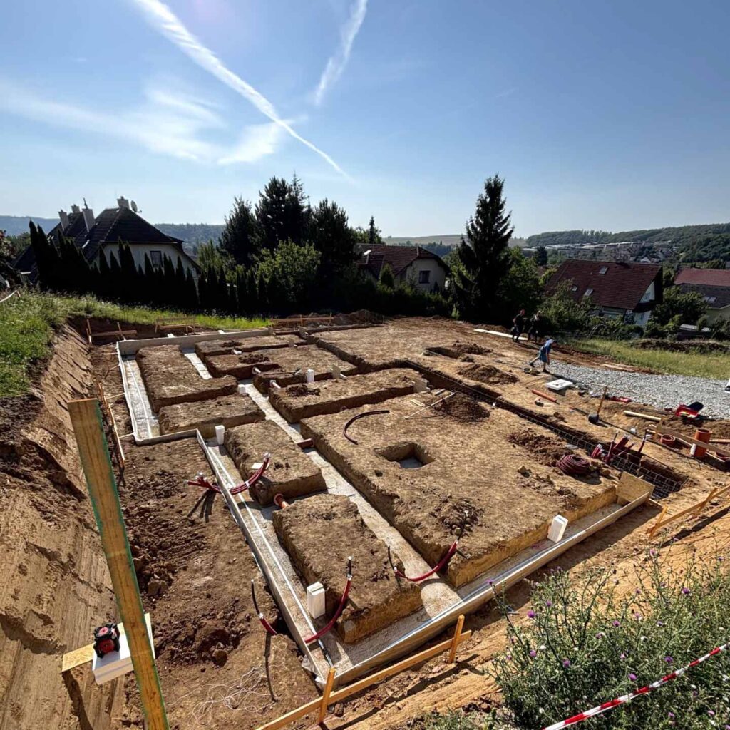 Výkopy základů rodinného domu na svažitém pozemku.