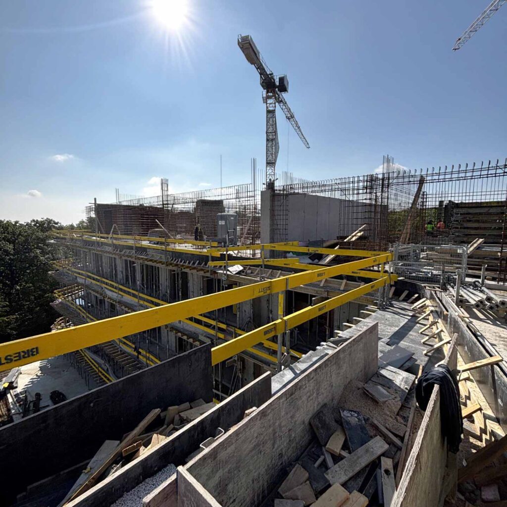 Detail železobetonové konstrukce během výstavby s věžovým jeřábem.