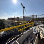 Detail železobetonové konstrukce během výstavby s věžovým jeřábem.