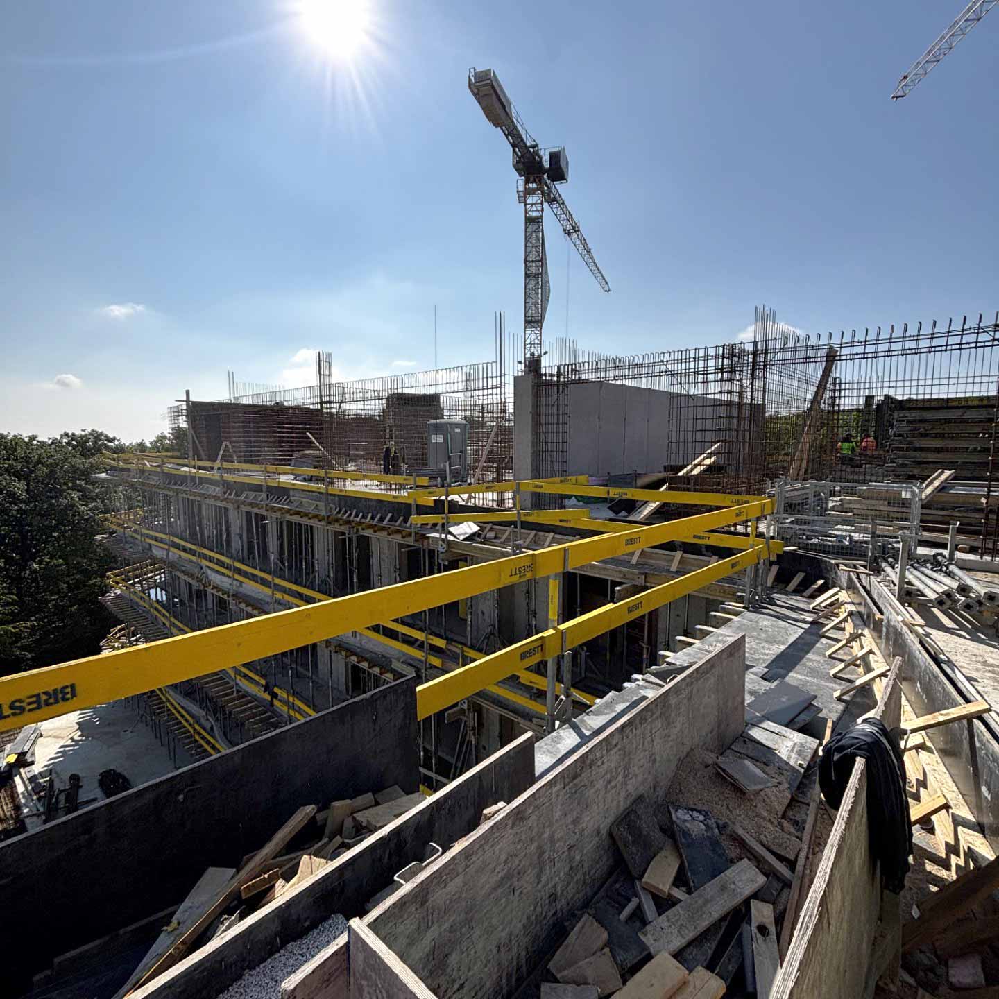 Detail železobetonové konstrukce během výstavby s věžovým jeřábem.